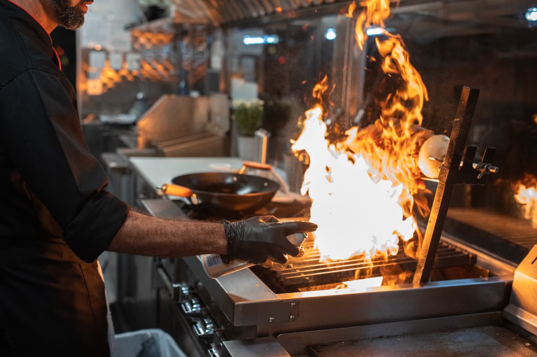 Koch grillt Fleisch über offener Flamme